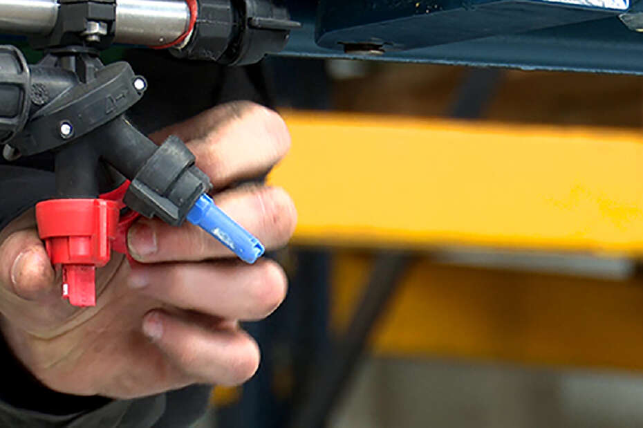 Hand umfasst eine Feldspritze in Nahaufnahme, um sie zu prüfen.