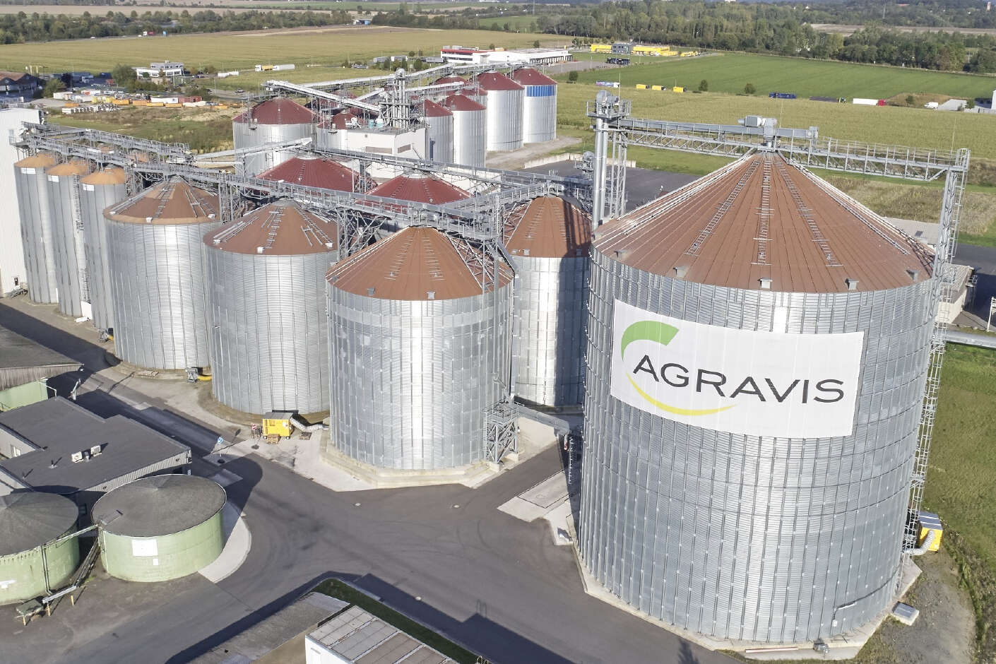Stahlsilos in verschiedenen Höhen nebeneinander, verbunden durch Elevatoren. Das Silo im Vordergrund ist das Größte. Im Hintergrund sind noch mehrere Stahlsilos zu erkennen. 