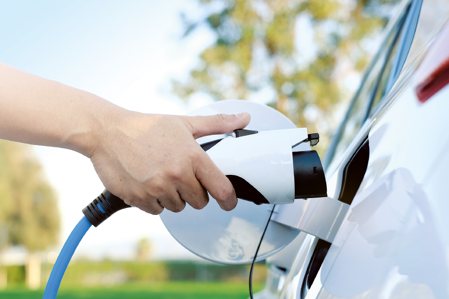 Ein weißes E-Auto wird von der Seite betankt.