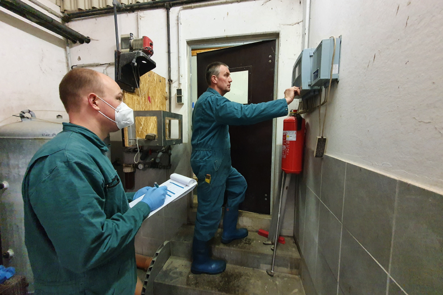 Zwei Männer überprüfen beim Stallklima- und Tränkewassercheck im Stall ein Gerät.