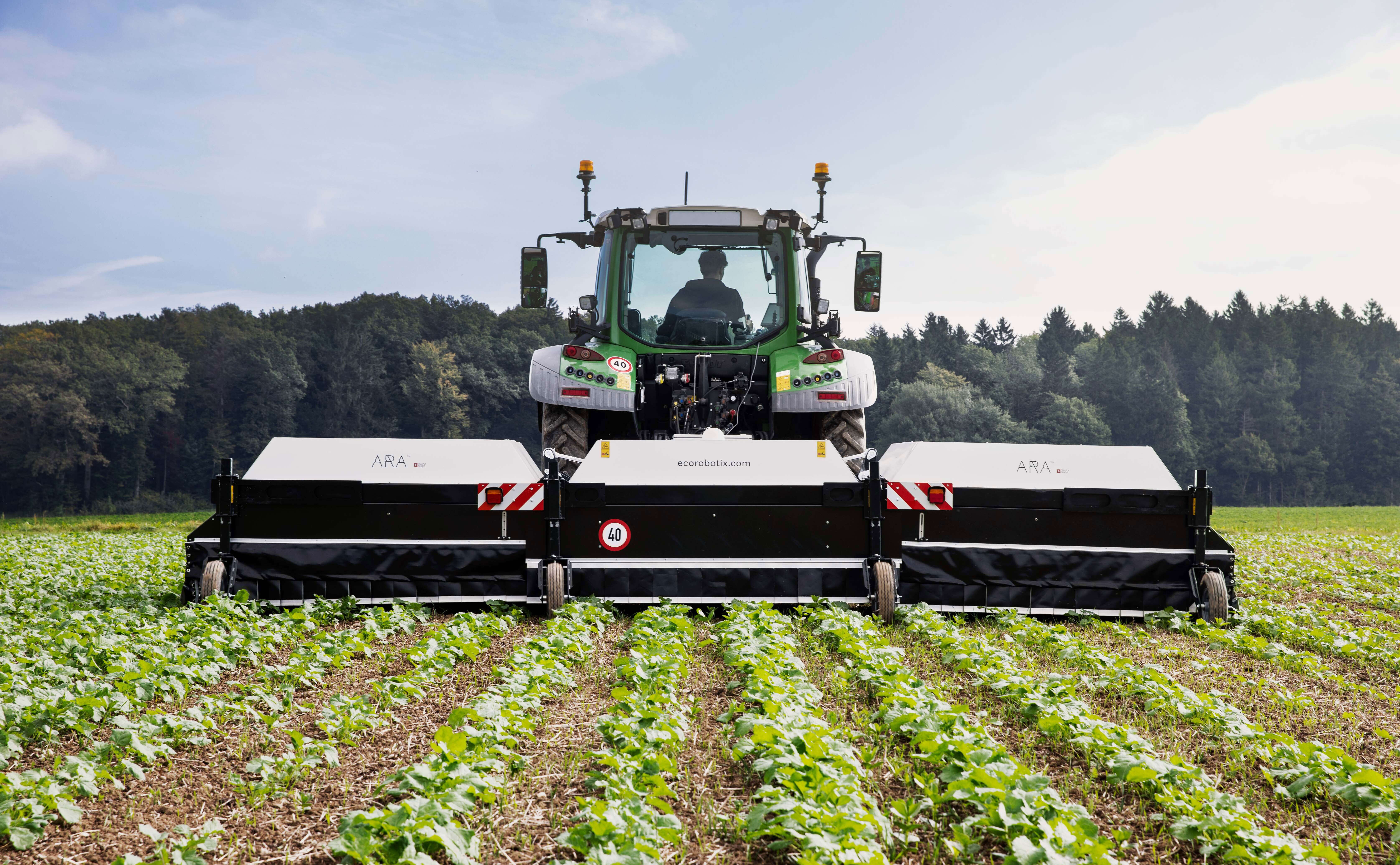 ARA Feldspritze von Ecorobotix hinter Traktor auf Rübenfeld bei Sonnenschein