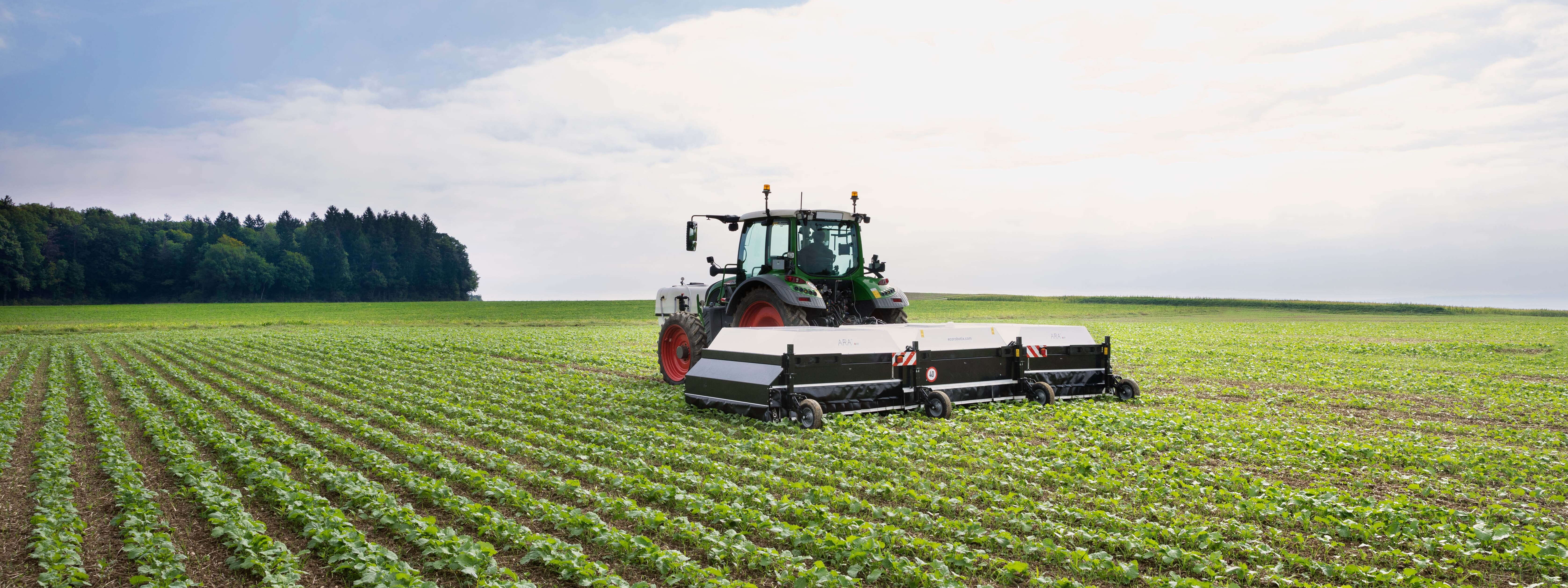 Eine ARA Feldspritze wird von einem Fendt Traktor über ein Feld gezogen.