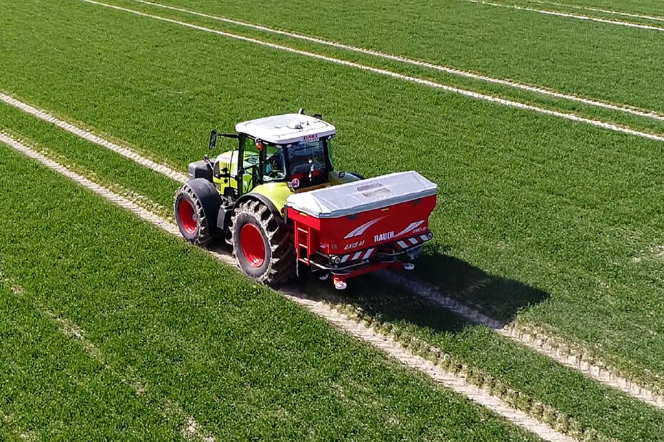 Claas Traktor mit Rauch-Düngerstreuer auf Feld