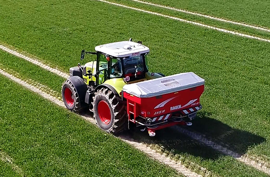 Claas Traktor mit Rauch-Düngerstreuer auf Feld