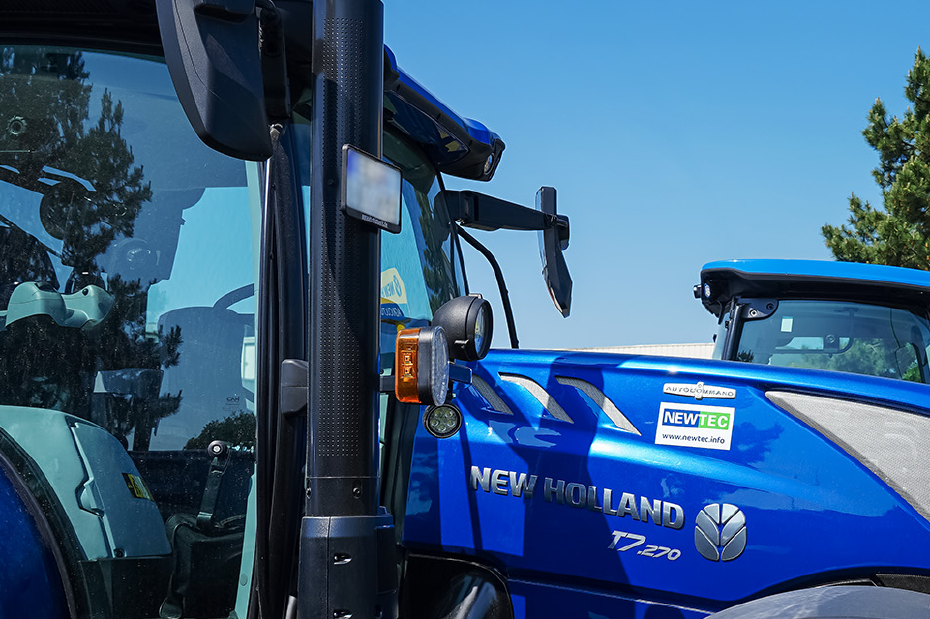 Blaue Schlepper von New Holland, im Hintergrund New Holland Schild