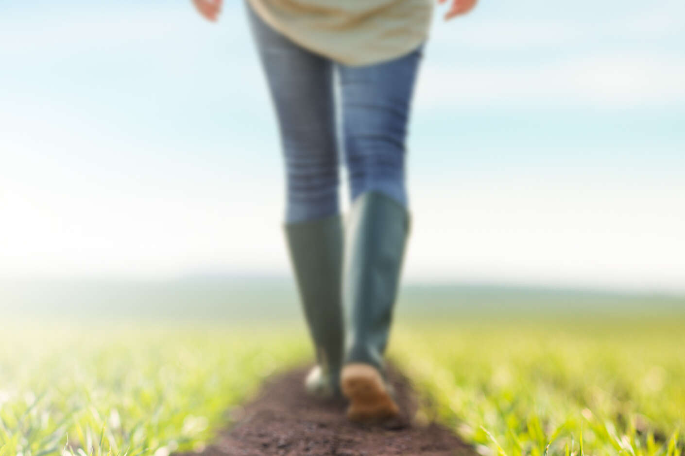 Eine Person läuft über ein Feld, es sind nur die Beine zu sehen.