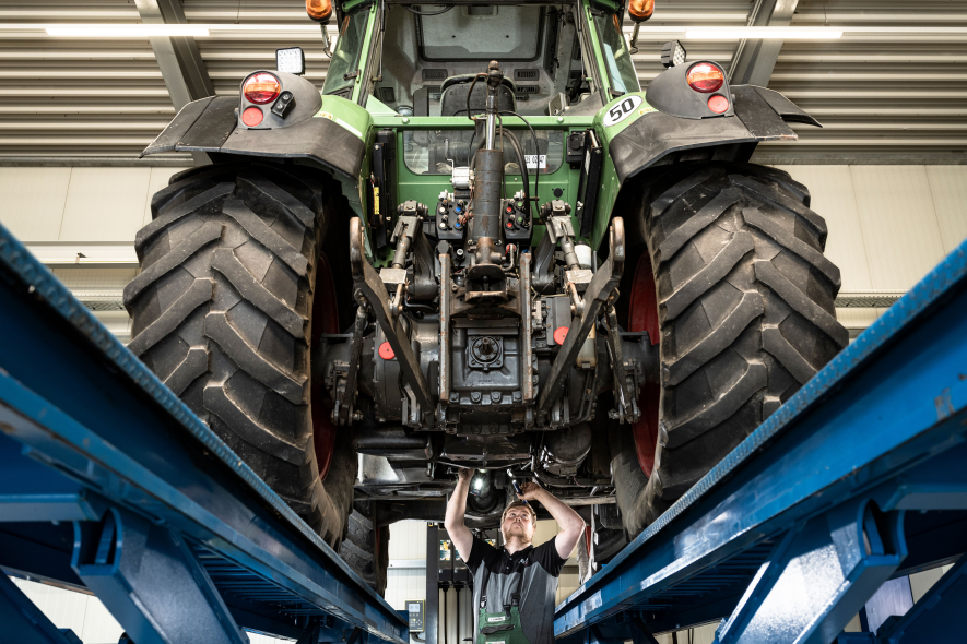 Technik-Mitarbeiter arbeitet an Schlepper auf Hebebühne