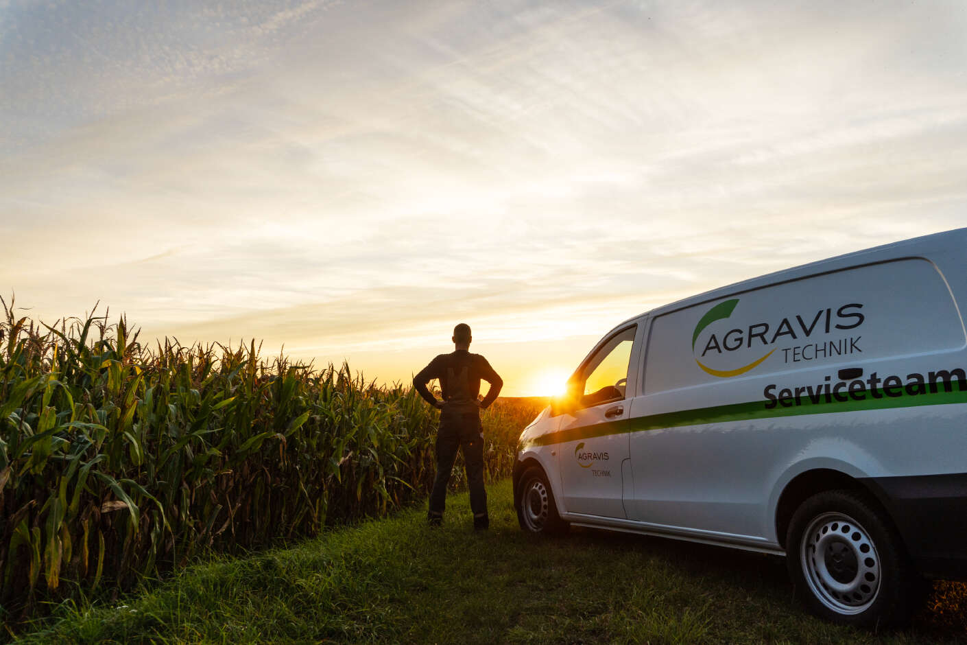 Servicetechniker bei Sonnenuntergang neben AGRAVIS Technik Transporter am Feldrand