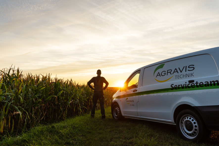 Servicetechniker bei Sonnenuntergang neben AGRAVIS Technik Transporter am Feldrand