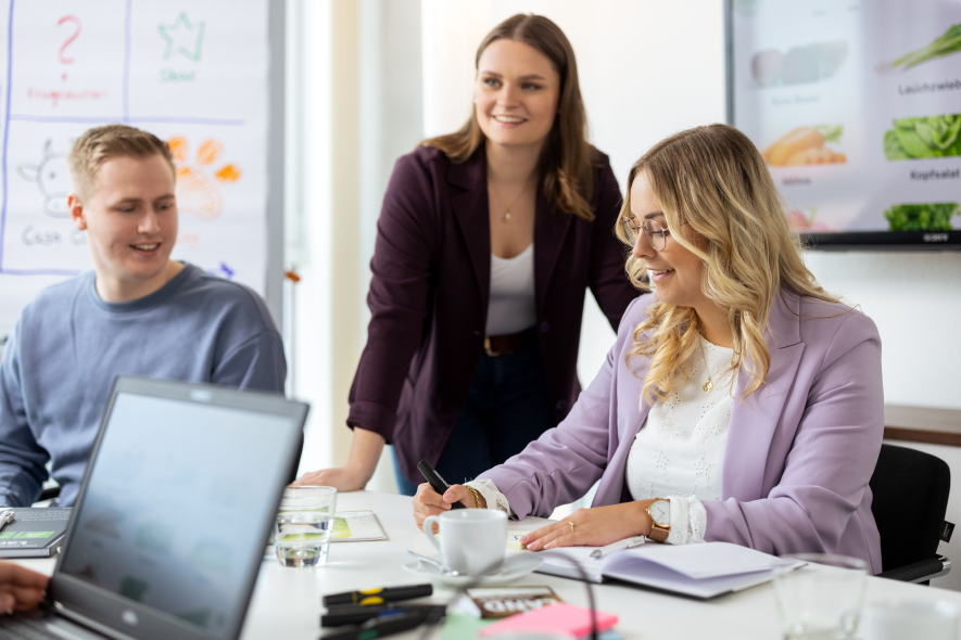 Drei Azubis sitzen zusammen in einem Meeting und planen Projekte.