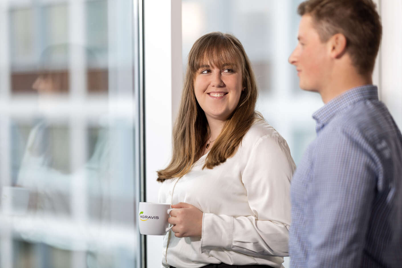 Trainees stehen an einem Fenster und trinken Kaffee