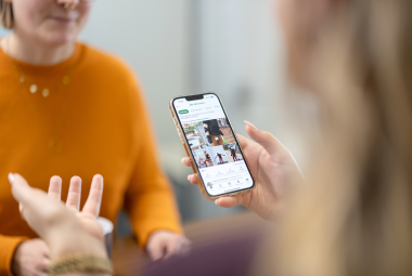 zwei Frauen unterhalten sich wärend eine ein Smartphone in der Hand hat