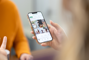zwei Frauen unterhalten sich wärend eine ein Smartphone in der Hand hat