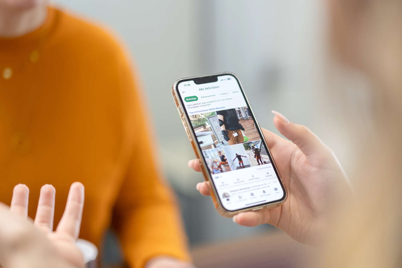 zwei Frauen unterhalten sich wärend eine ein Smartphone in der Hand hat