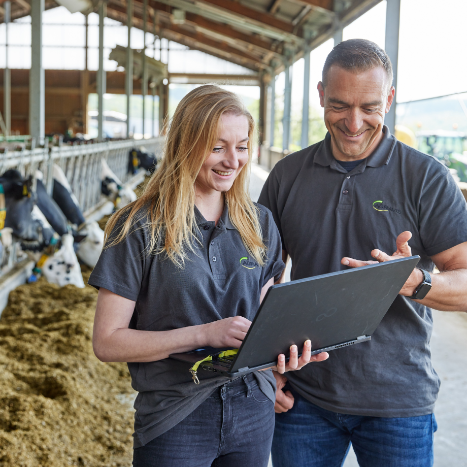 Consultant in front of feeding table in cattle barn with laptop in hand