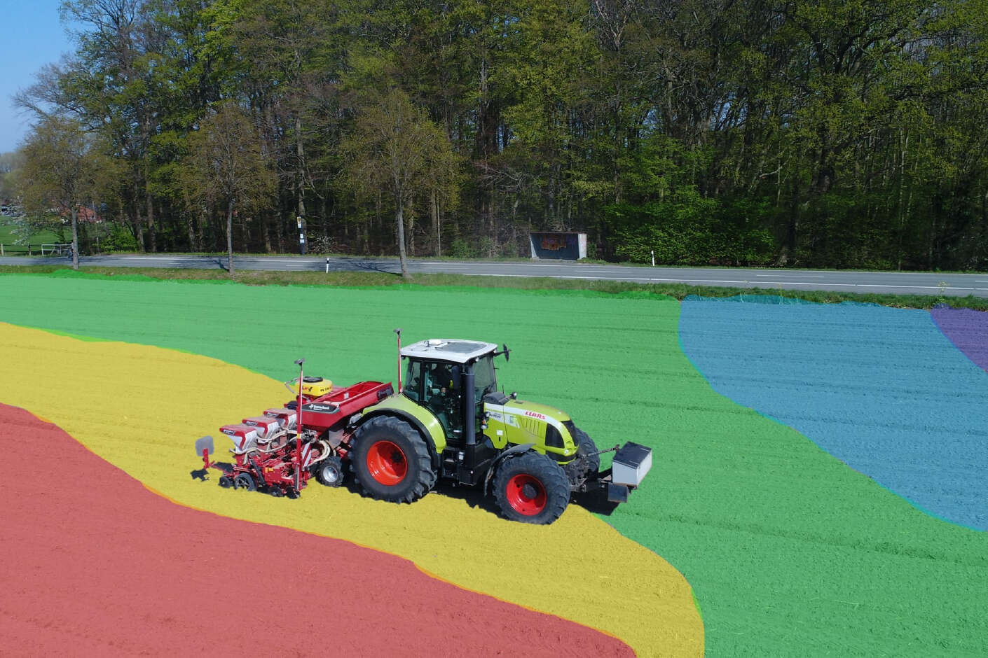 Claas fährt mit Sämaschine übers Feld welches durch NetFarming in unterschiedliche Bereiche farblich eingeteilt wurde