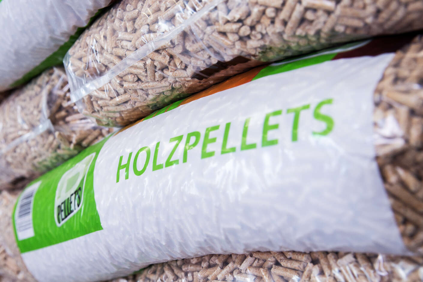 Säcke mit Holzpellets der Marke R-Pellets liegen übereinandergestapelt in einer Lagehalle.