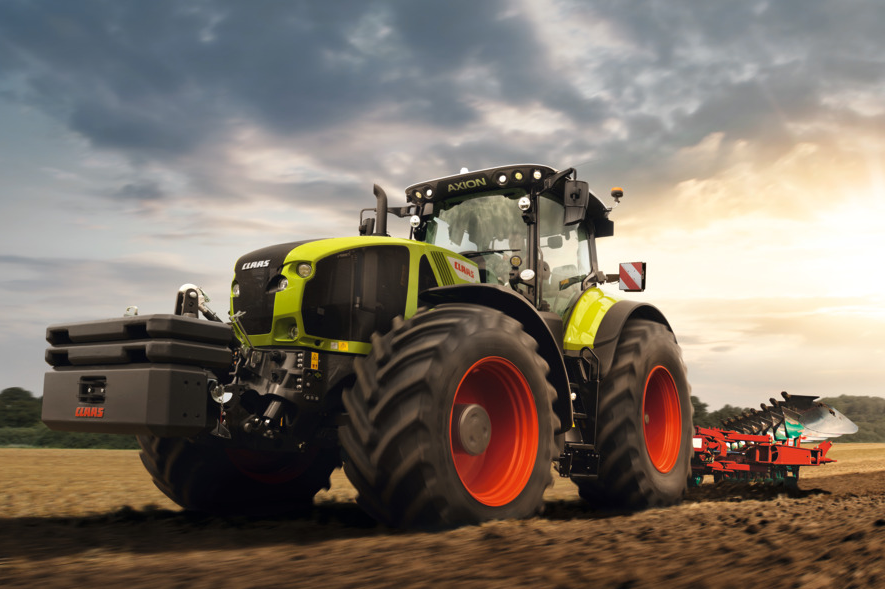 CLAAS AXION Traktor beim Pflügen eines Ackers mit Anbaupflug am frühen Abend
