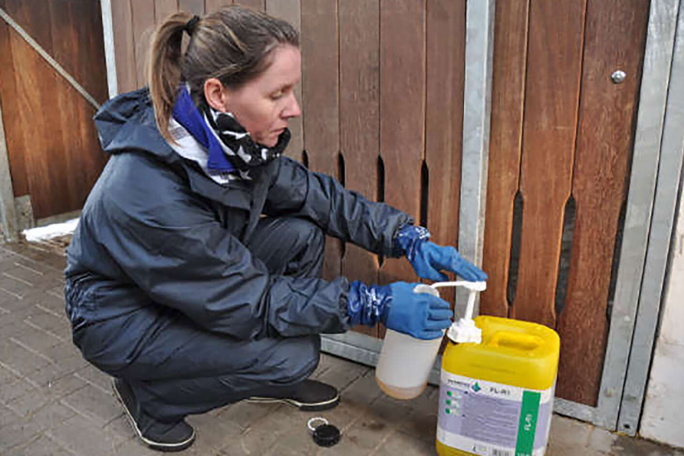 Eine Frau pumpt in einem Stall Hygienemittel in eine Sprühflasche