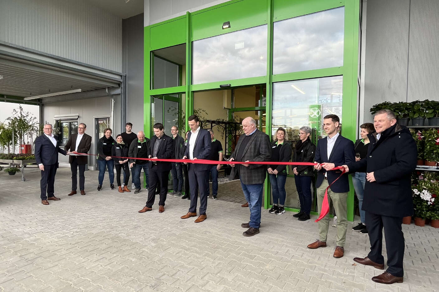 Mehrere Menschen vor dem Eingang des Raiffeisenmarktes bei der Eröffnung. 