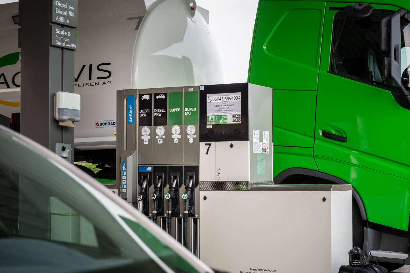 Tankstelle mit Auto im Vordergrund und Tanksäule und LKW im Hintergrund