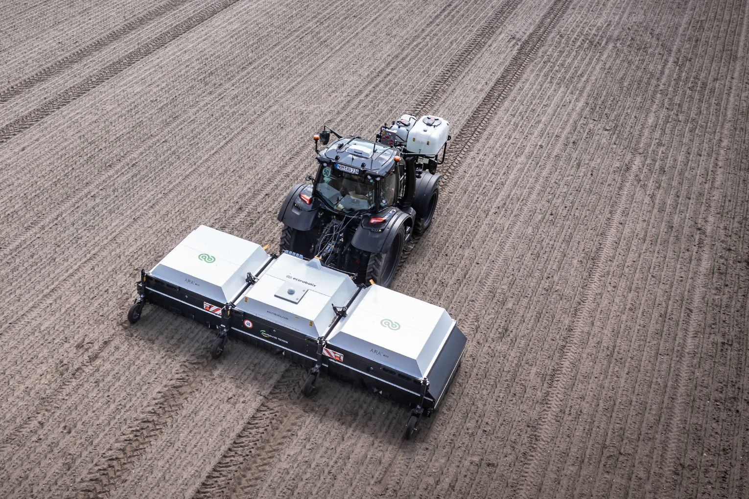 Ecorobotix ARA Feldspritze wird von einem Traktor über ein Feld gezogen