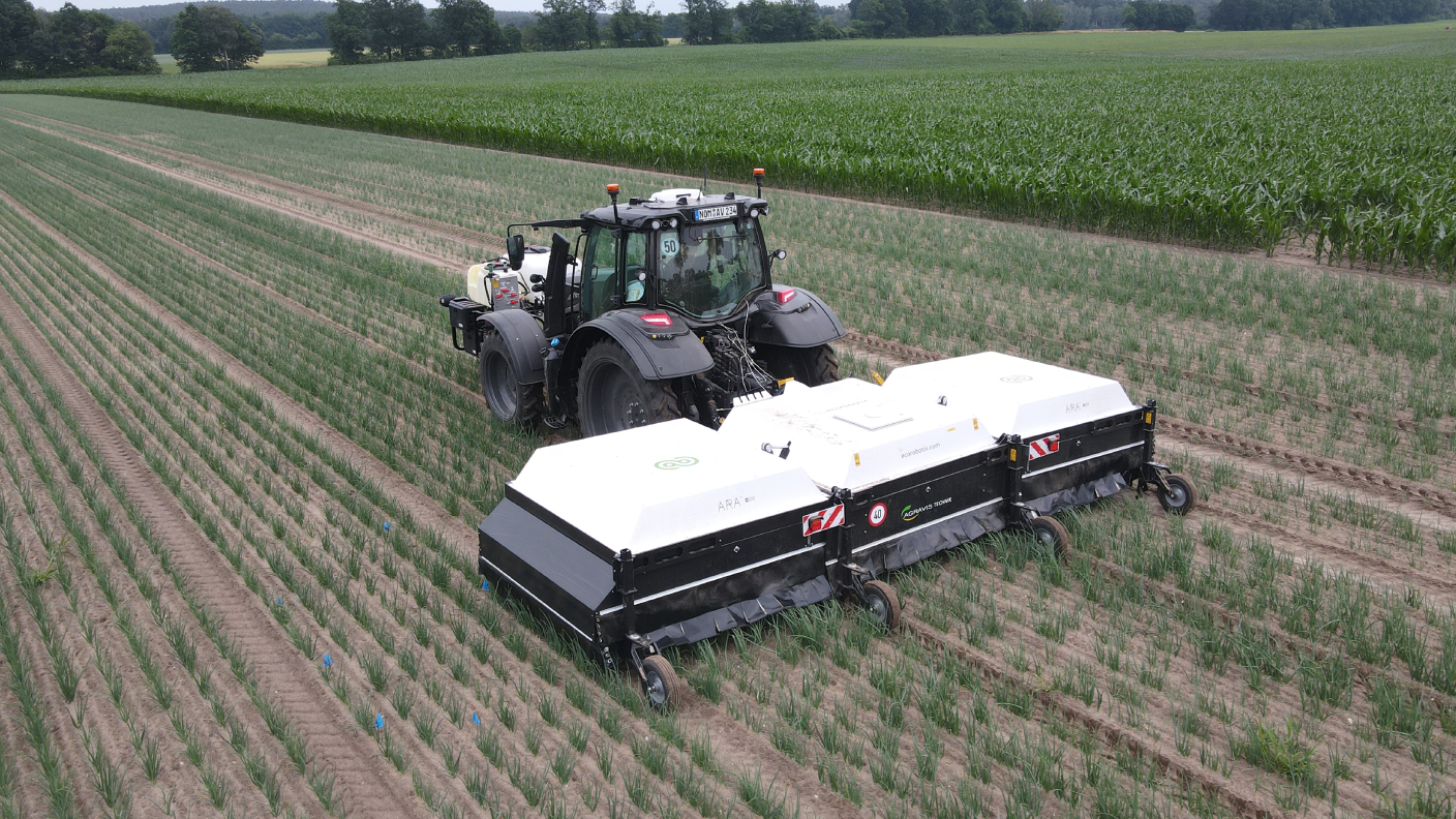ARA ecoRobotix Feldspritze hinter Traktor im Zwiebelfeld der AGRAVIS Future Farm