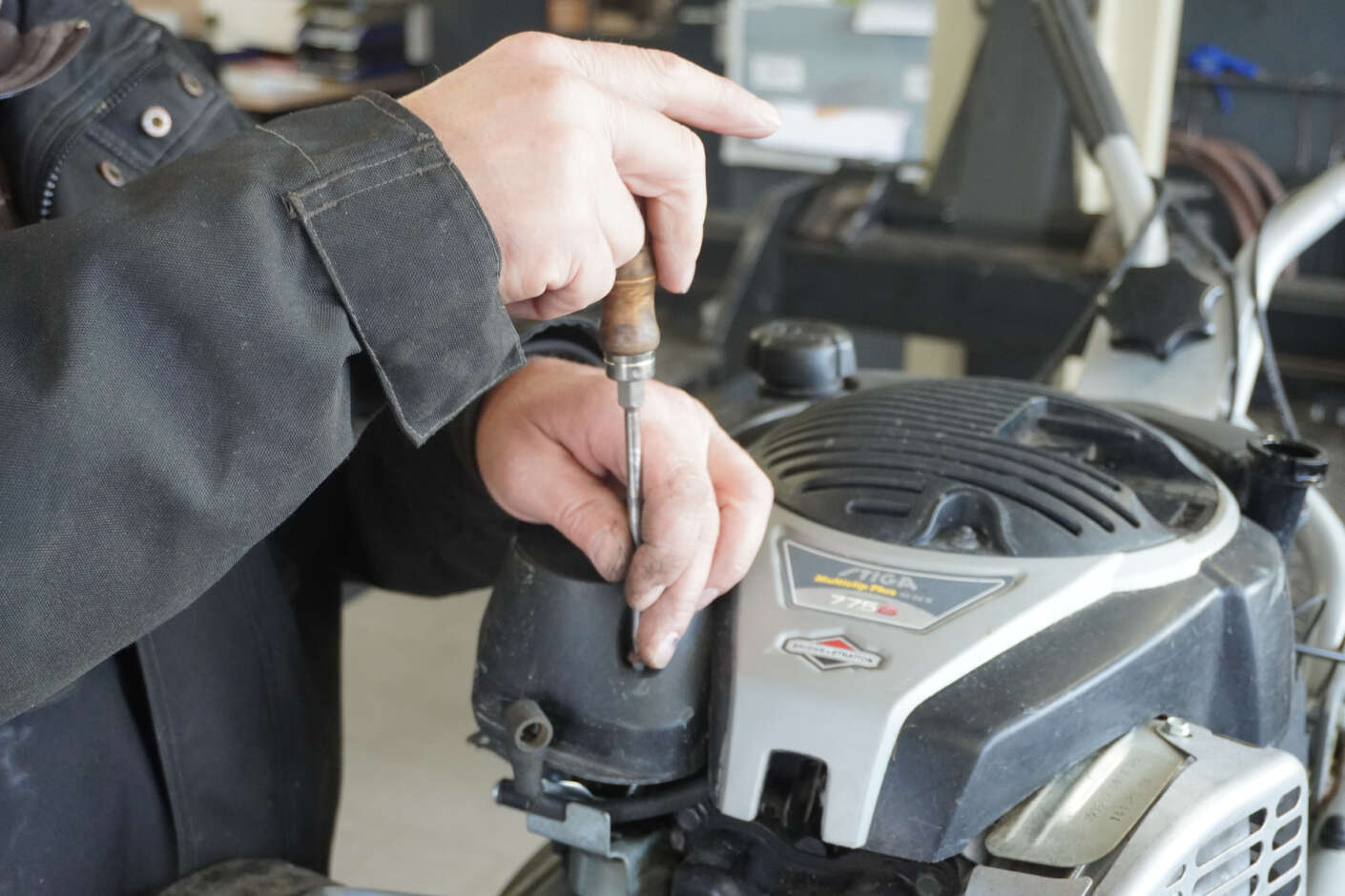 Detailaufnahme eines Mitarbeiters bei einer Rasenmäherreparatur 