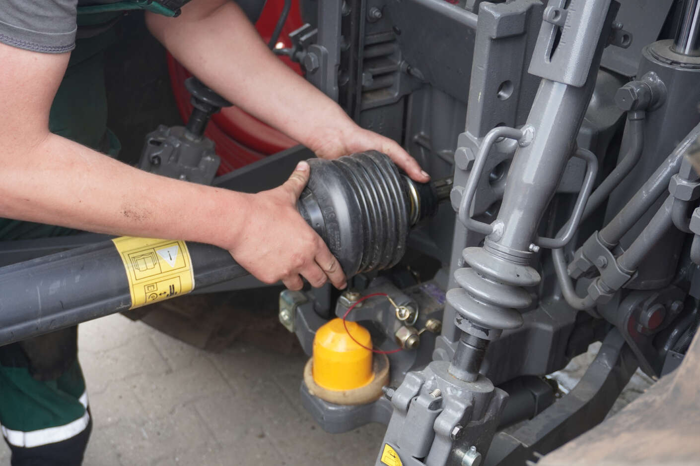 Mechaniker beim Anbau einer Gelenkwelle an einem Schlepper
