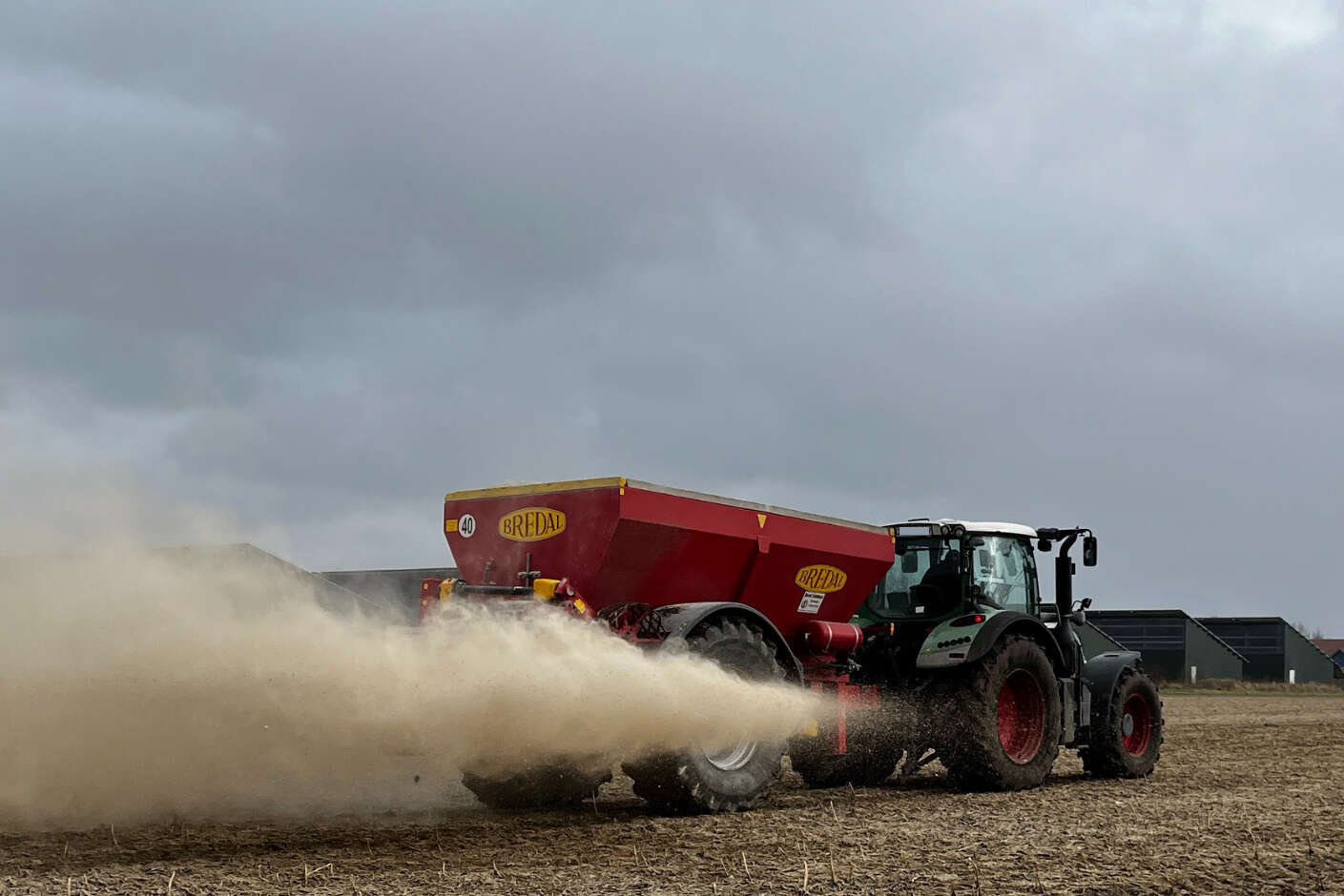 Trecker bringt mit Bredal-Kalkstreuer Kalk auf dem Feld aus