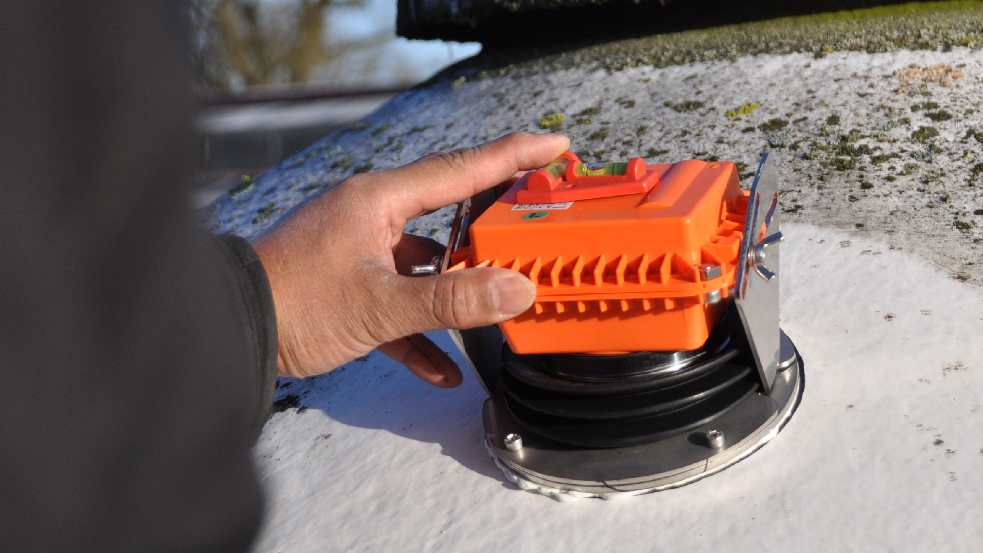 Der orangene RSilo-Radarsensor wird auf GFK-Silodach geklebt