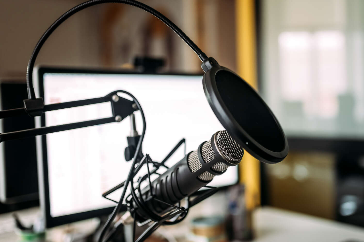Podcastaufnahme im Studio mit Rechner und Mikrofon.