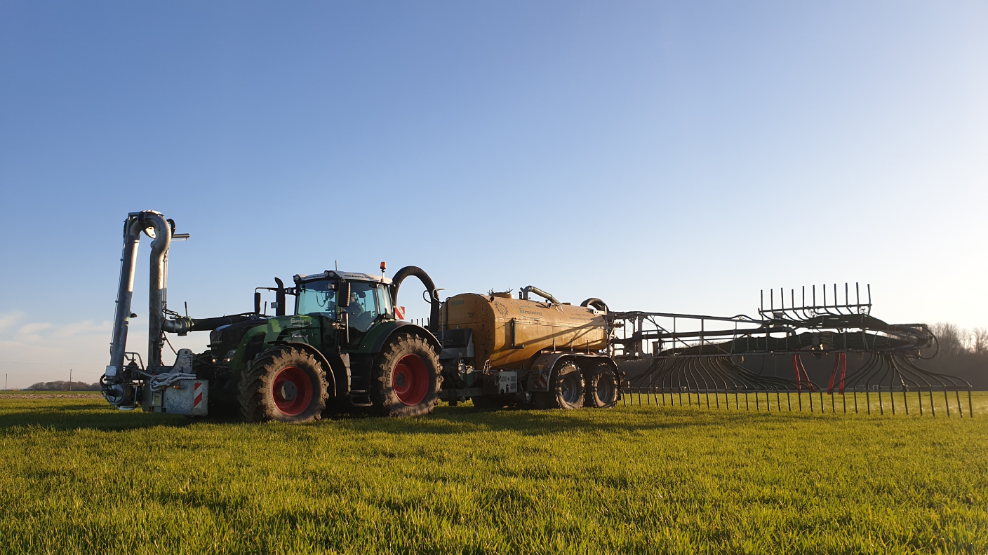 Trecker fährt Gülle auf einem Feld