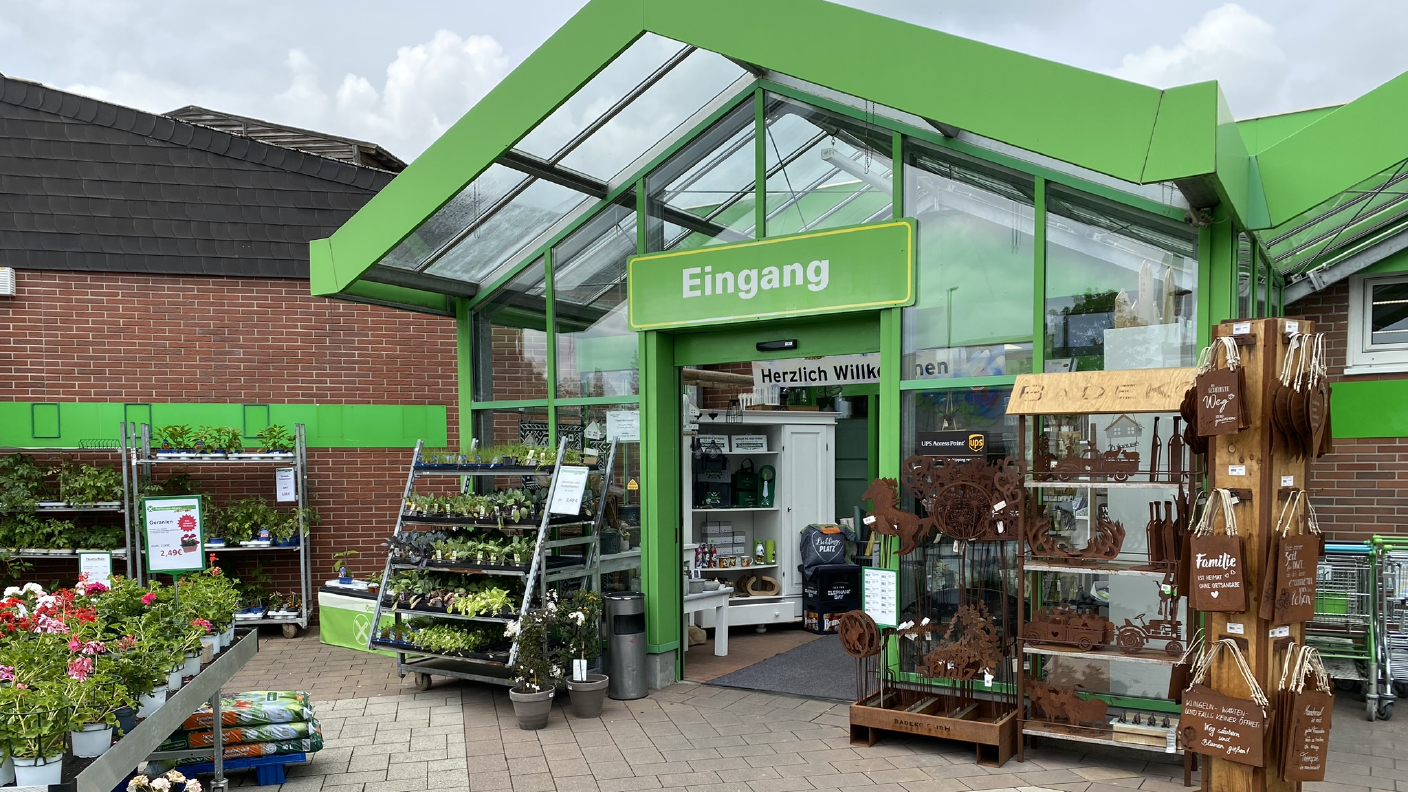 Eingang zum Raiffeisen-Markt Warburg mit Pflanzen & Deko im Vordergrund