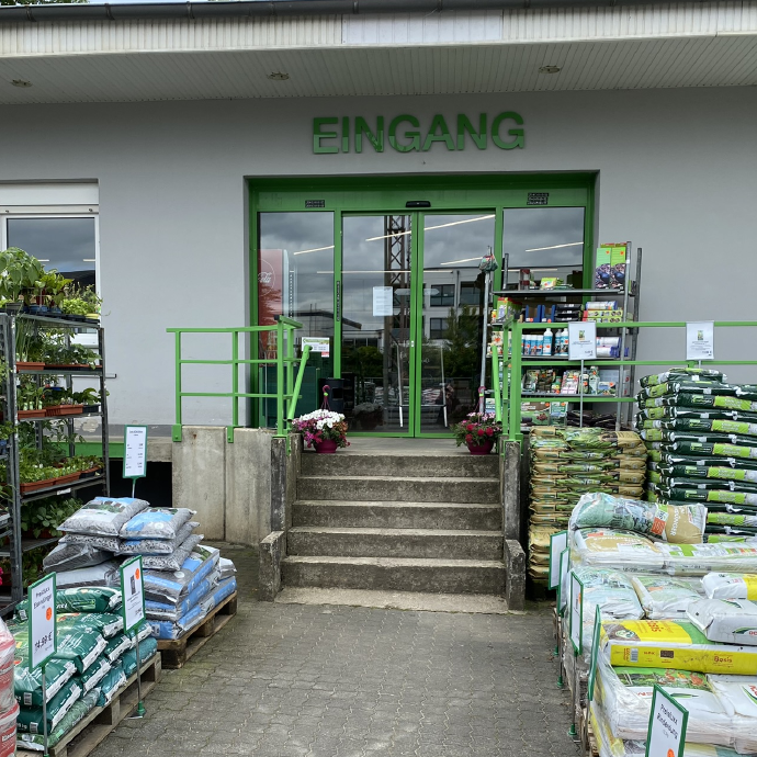 Eingang zum Raiffeisen Markt Grevenbrück Lennestadt mit Blumeerde & Dünger im Vordergrund