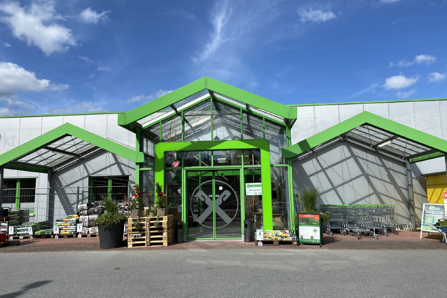 Eingang vom Raiffeisen-Markt Meschede mit Pflanzen, Gartenbedarf & Einkaufswagen im Vordergrund