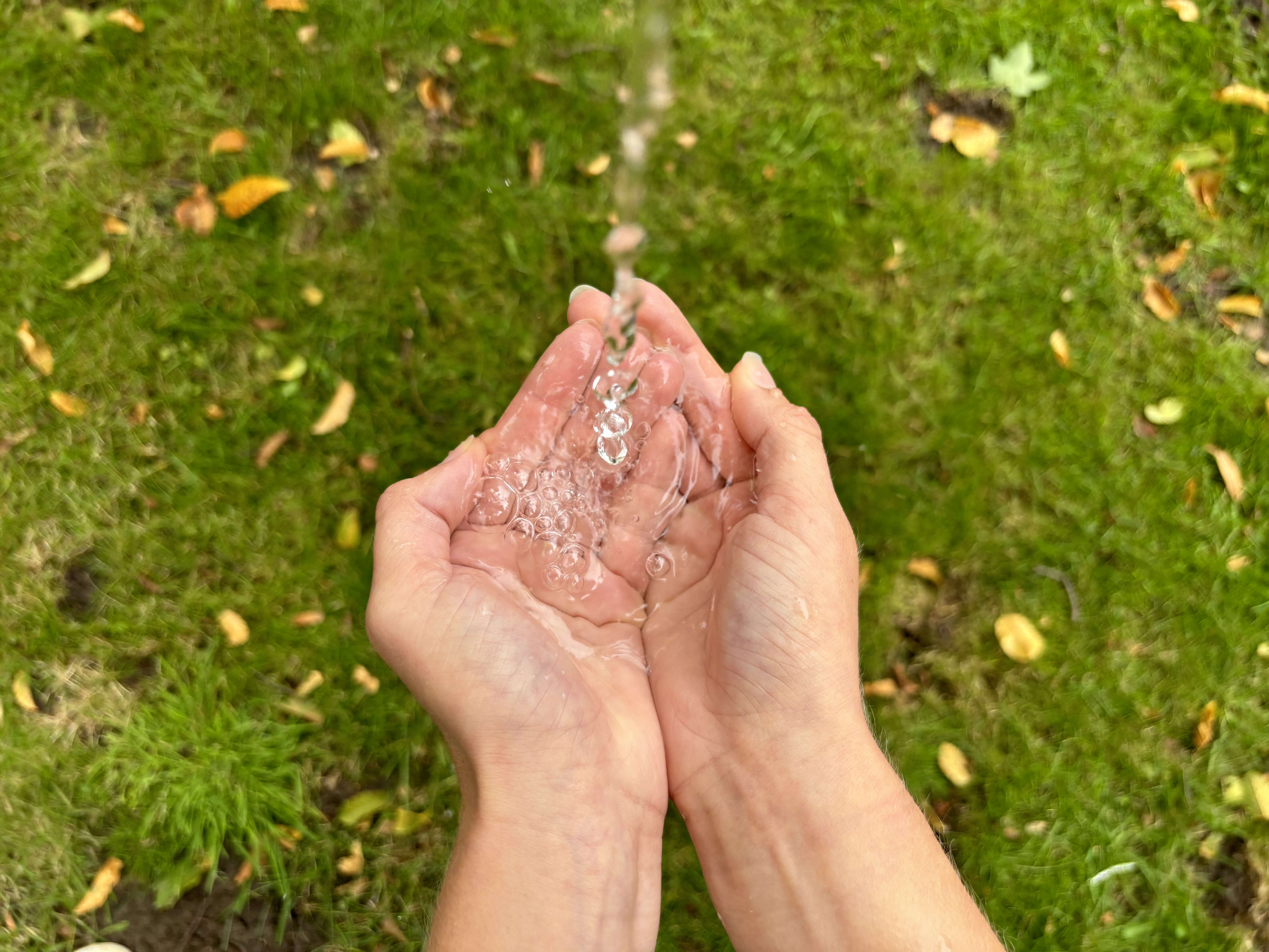 Wasser läuft von oben in zwei Hände