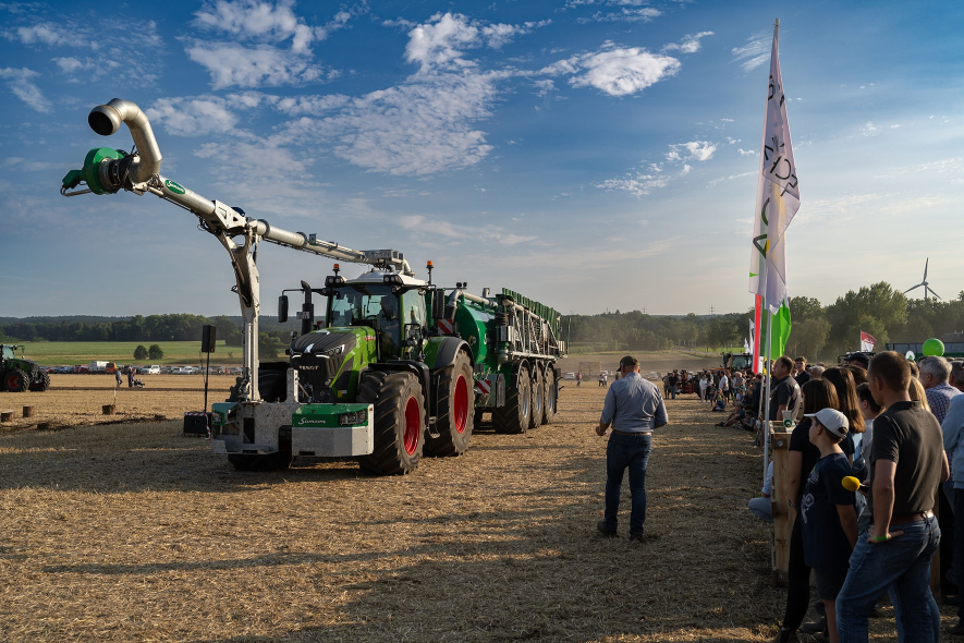 Vorführung mit Güllefass und Traktor auf Feld vor Publikum
