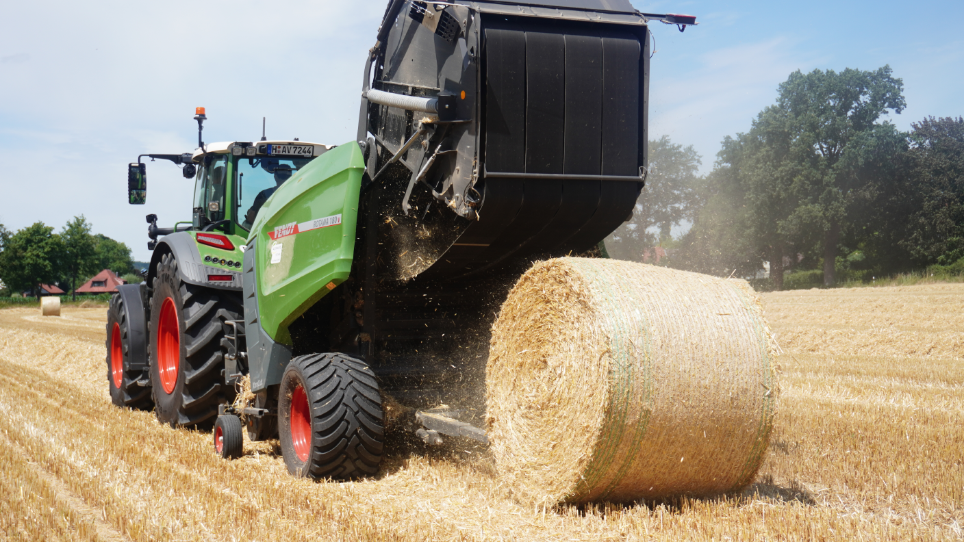 Fendt-Traktor mit Rundballenpresse beim Auswerfen eines Ballens