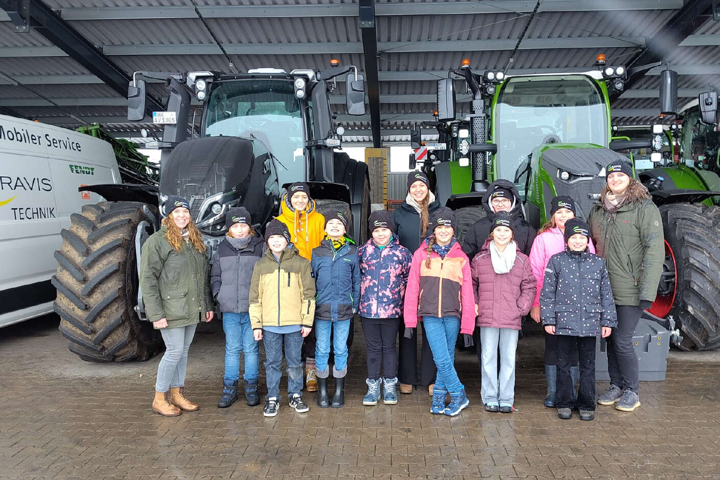 Eine Gruppe von Grundschulkindern steht vor zwei Traktoren. 