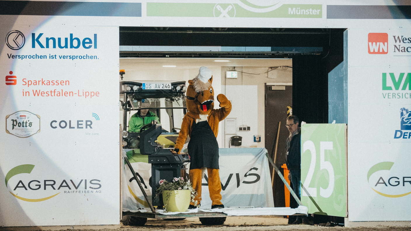 Kleiner Trecker fährt Pferde-Maskottchen mit Grill in Reithalle