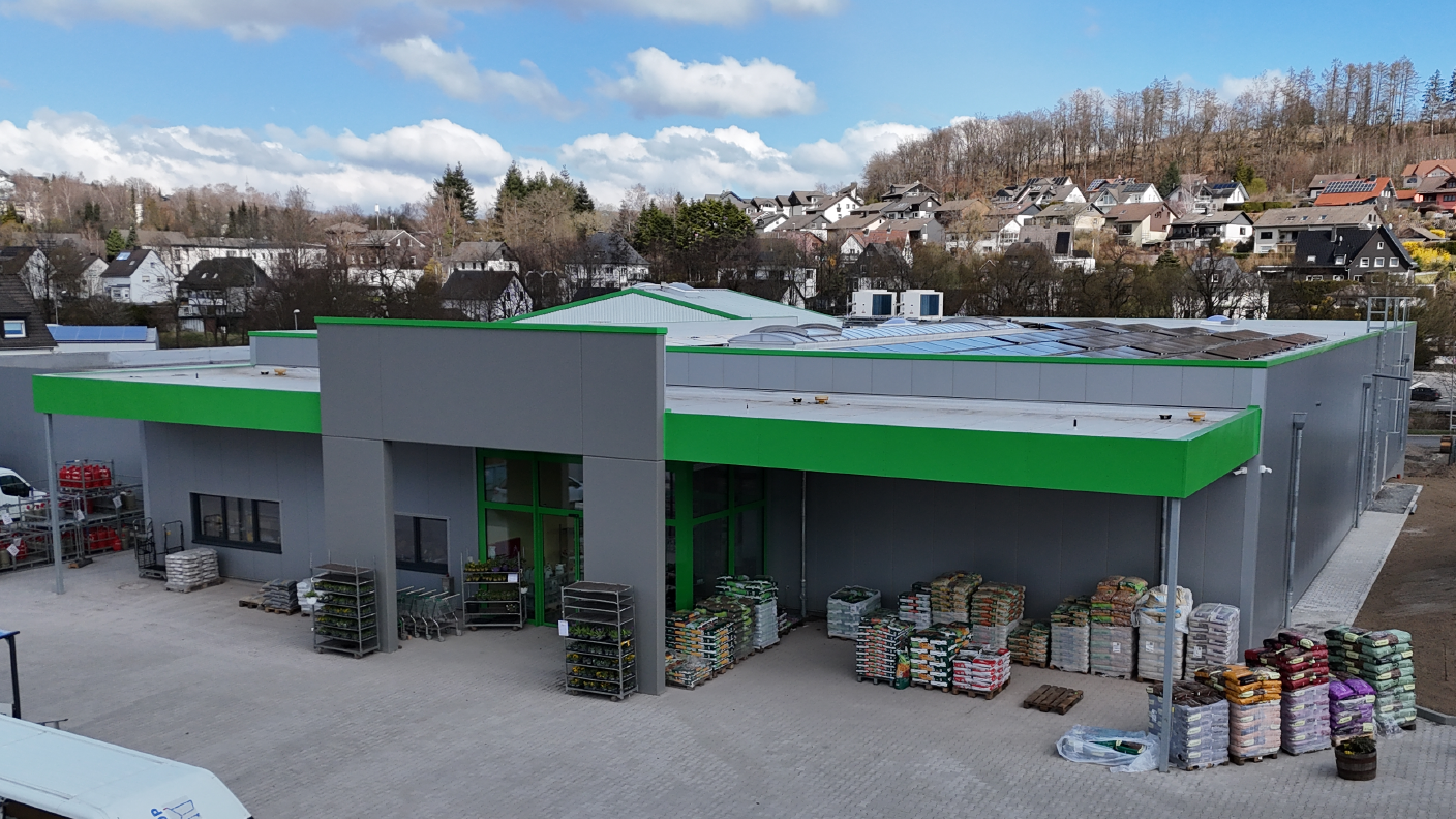 Hauptfassade des Anbaus des Raiffeisenmarkts in Herscheid. Die Aufschirft "Raiffeisenmarkt" auf dem Eingangsportal fehlt noch. Links im Bild sieht man das Bestandsgebäude an das angebaut wurde.