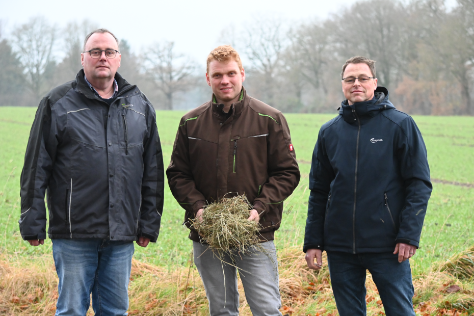 Gerken, Bardenhagen und Helmers stehen mit Heu in der Hand am Feld.