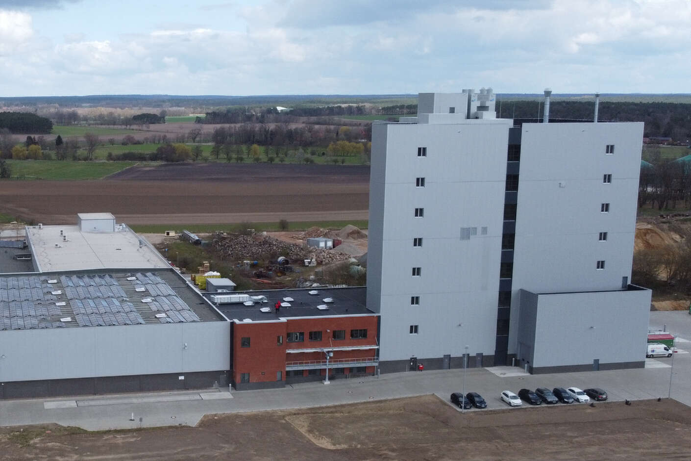 Drohnenaufnahme vom Mühlengebäude in Rosche. Im Vordergrund ist ein Klinkergebäude, im Hintergrund steht der hohe Mühlenturm. 