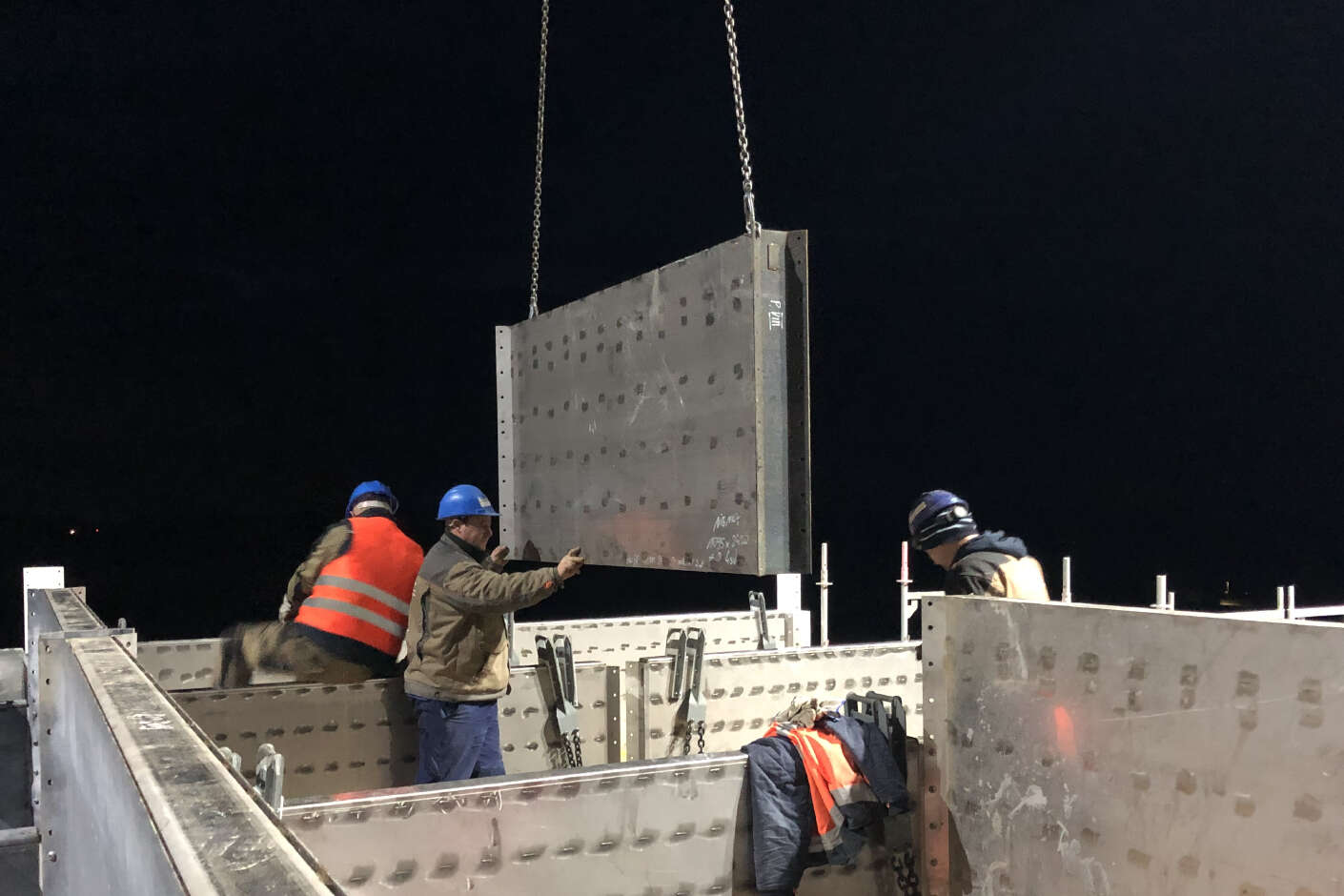 Drei Bauarbeiter auf der Baustelle montieren Stahlwände.