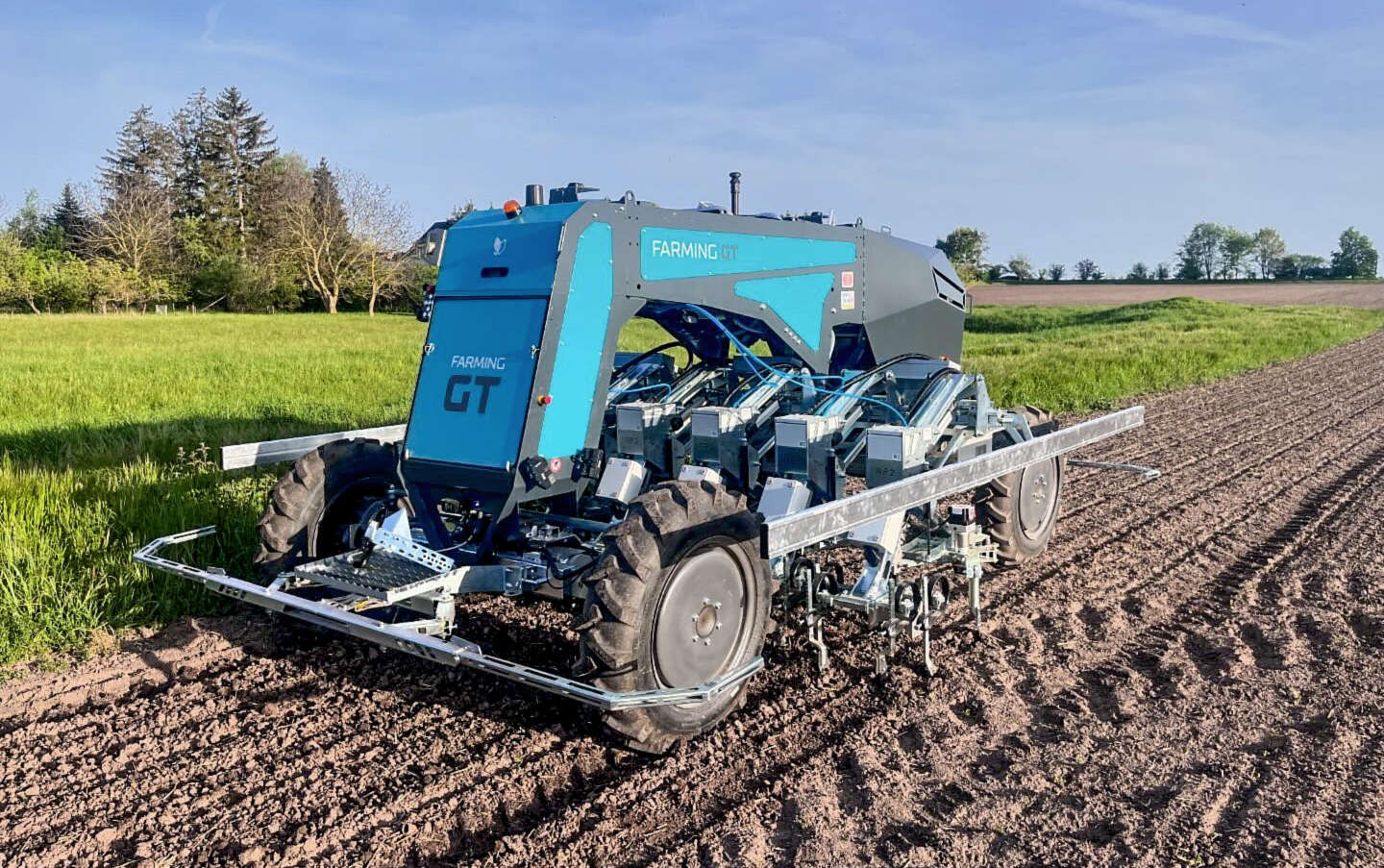 Farming GT fährt autonom über frisch bearbeiteten Acker neben einer grünen Wiese
