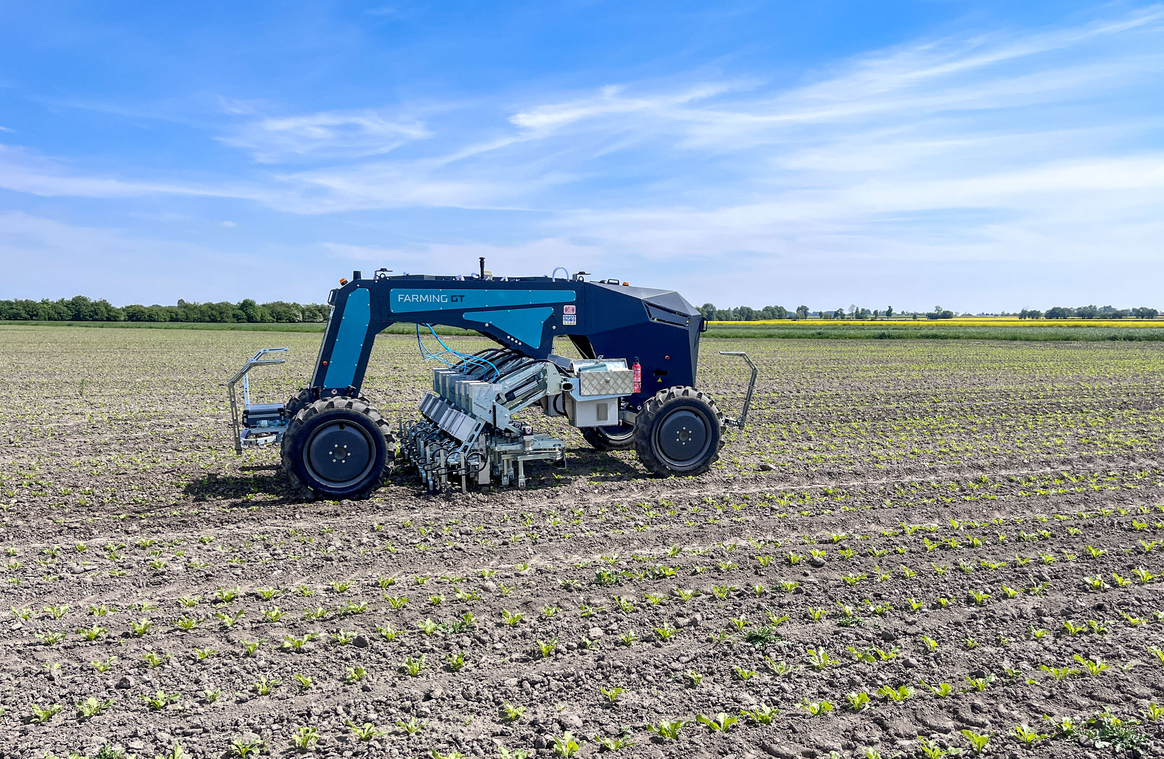 Autonomer Farming GT arbeitet auf jung bepflanztem Acker unter blauem Himmel