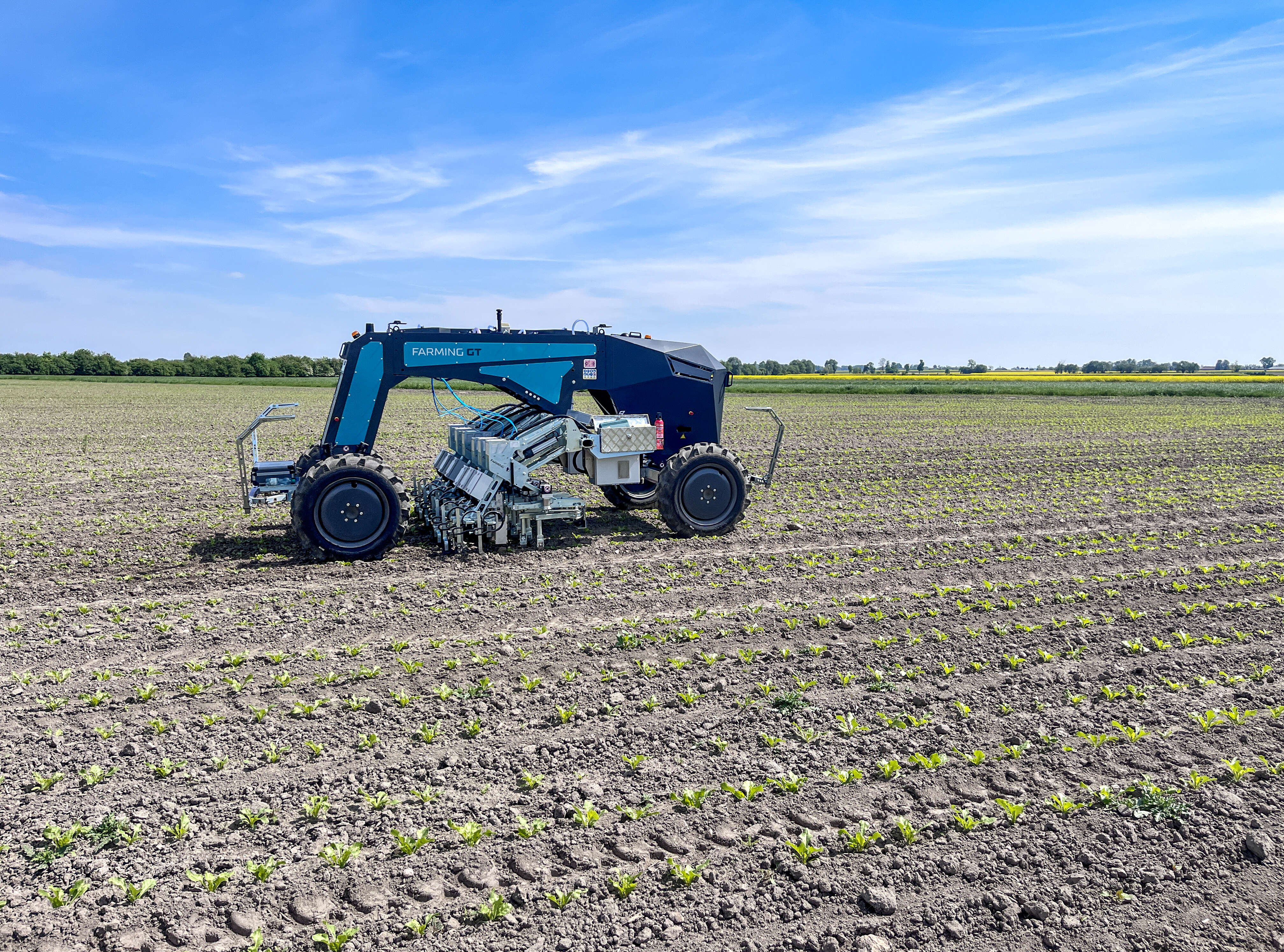 Autonomer Farming GT arbeitet auf jung bepflanztem Acker unter blauem Himmel