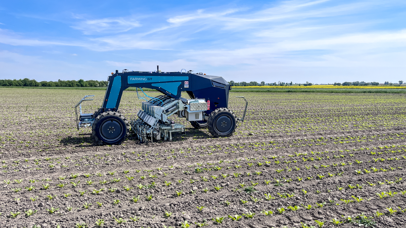 Autonomer Farming GT arbeitet auf jung bepflanztem Acker unter blauem Himmel
