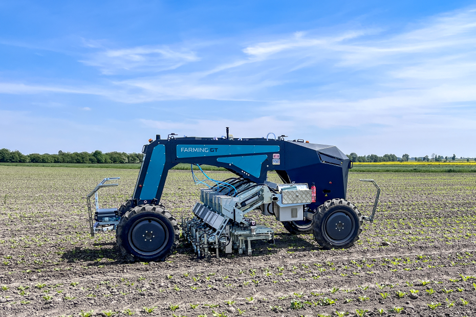 Autonomer Farming GT arbeitet auf jung bepflanztem Acker unter blauem Himmel